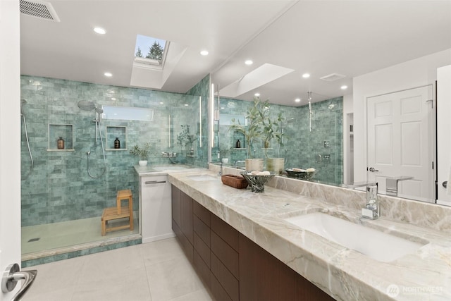 bathroom with a stall shower, a skylight, visible vents, and a sink