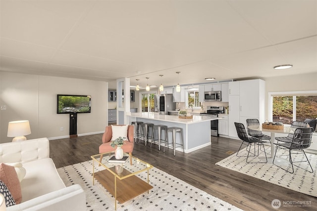 living room with a wealth of natural light, baseboards, and dark wood-type flooring