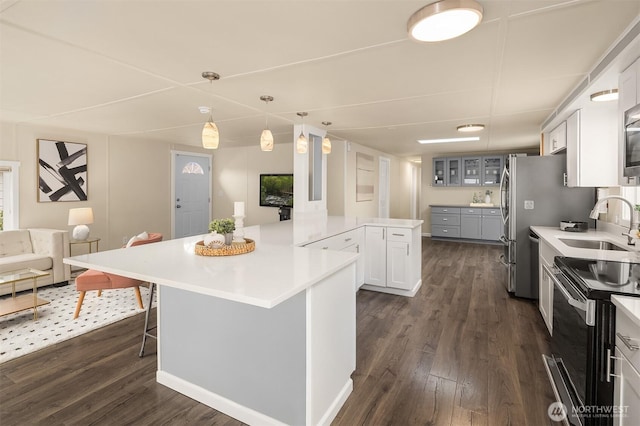 kitchen with dark wood-style flooring, a sink, glass insert cabinets, range with electric stovetop, and a kitchen breakfast bar