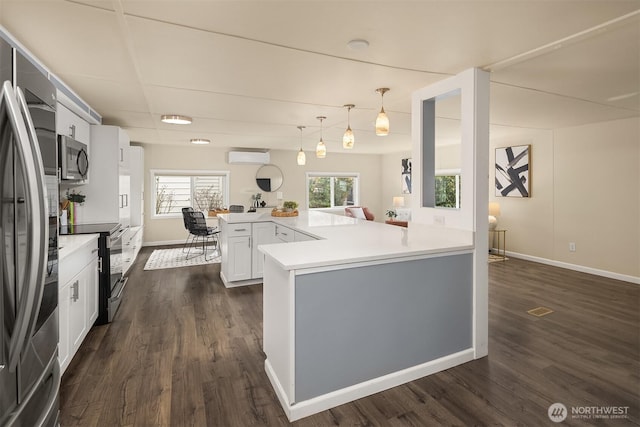 kitchen featuring dark wood finished floors, appliances with stainless steel finishes, a peninsula, and a wall unit AC