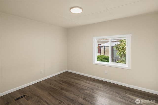 unfurnished room with dark wood finished floors, visible vents, and baseboards