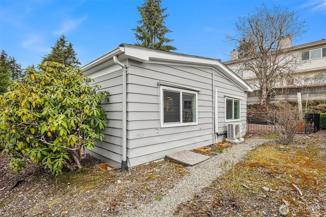 view of side of property with an outbuilding, ac unit, and fence