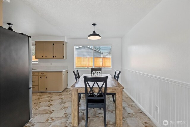 dining space with a textured ceiling and wainscoting