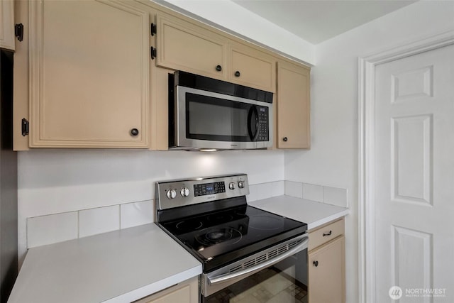 kitchen featuring light countertops, cream cabinetry, and appliances with stainless steel finishes