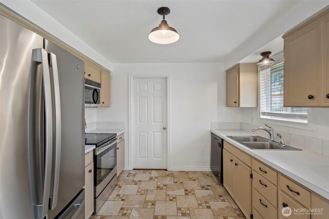 kitchen featuring baseboards, a sink, stainless steel appliances, light countertops, and cream cabinetry