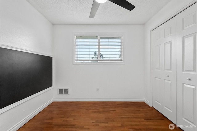 unfurnished bedroom with visible vents, baseboards, wood finished floors, a closet, and a textured ceiling