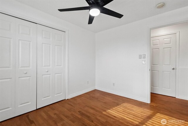 unfurnished bedroom featuring a ceiling fan, wood finished floors, a closet, and baseboards