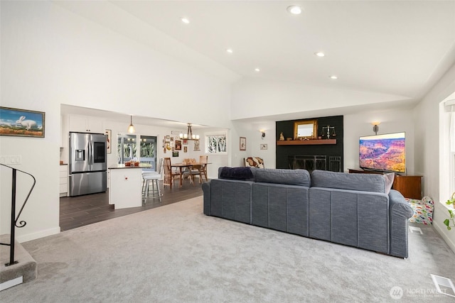 living area featuring visible vents, high vaulted ceiling, dark carpet, recessed lighting, and an inviting chandelier