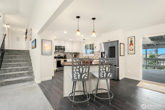 kitchen featuring tasteful backsplash, dark countertops, white cabinetry, stainless steel appliances, and wood tiled floor