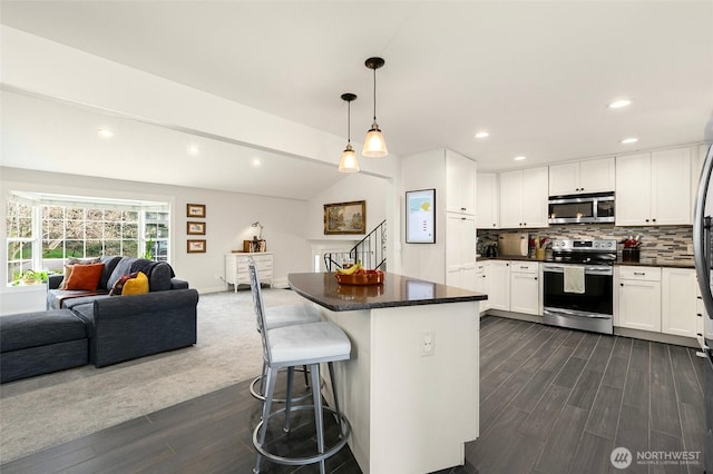 kitchen with white cabinets, tasteful backsplash, open floor plan, and stainless steel appliances