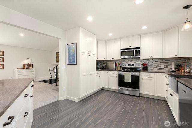 kitchen featuring white cabinets, tasteful backsplash, appliances with stainless steel finishes, and wood tiled floor