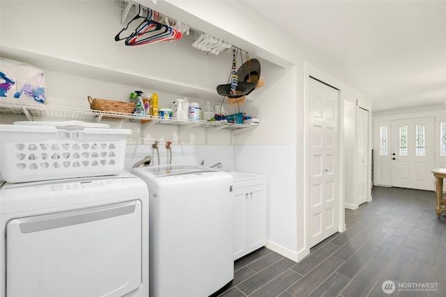 laundry area with wood finish floors, cabinet space, washing machine and dryer, and a sink