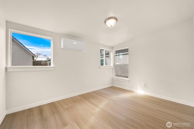 unfurnished room featuring an AC wall unit, wood finished floors, and baseboards