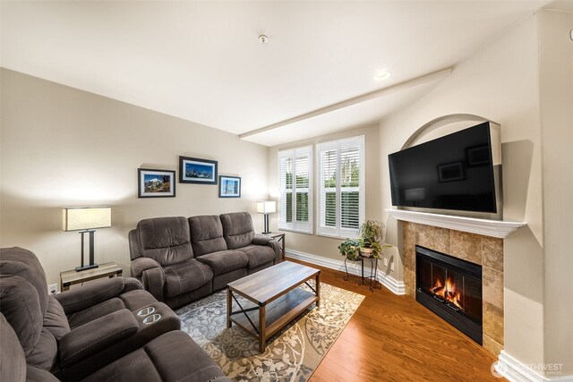 living room with a tiled fireplace, wood finished floors, and baseboards