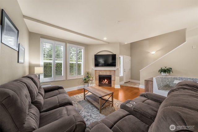 living area featuring baseboards, wood finished floors, and a tile fireplace