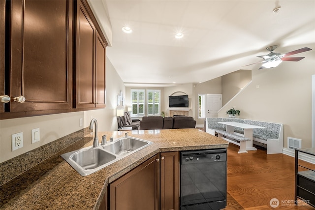 kitchen featuring a peninsula, dark wood-style flooring, a sink, black dishwasher, and open floor plan