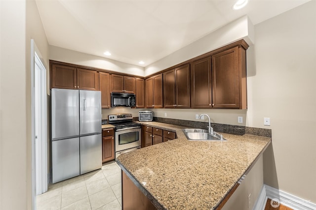 kitchen featuring stone counters, a peninsula, recessed lighting, a sink, and stainless steel appliances