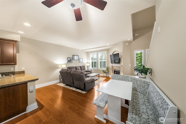 living area with wood finished floors, recessed lighting, baseboards, ceiling fan, and a tile fireplace