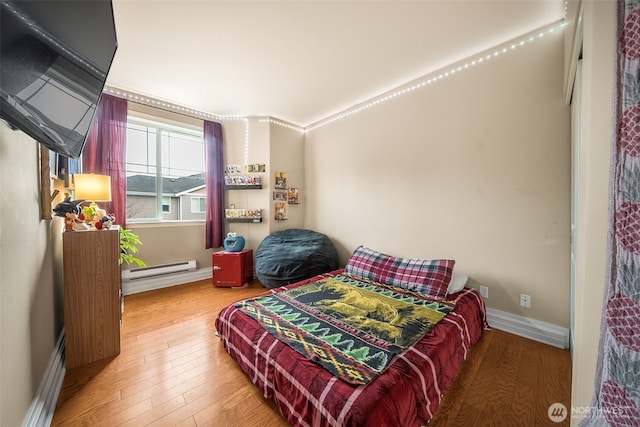 bedroom with a baseboard radiator, baseboards, and wood finished floors