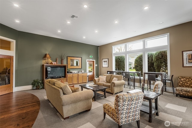 living area with recessed lighting, visible vents, and baseboards