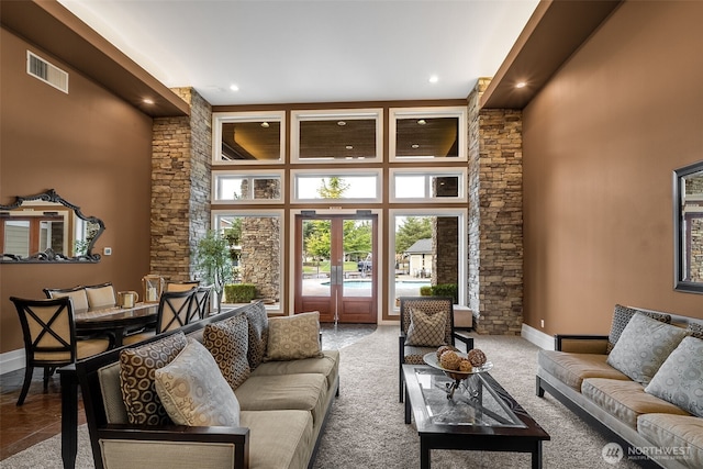 carpeted living area featuring visible vents, french doors, baseboards, and a towering ceiling