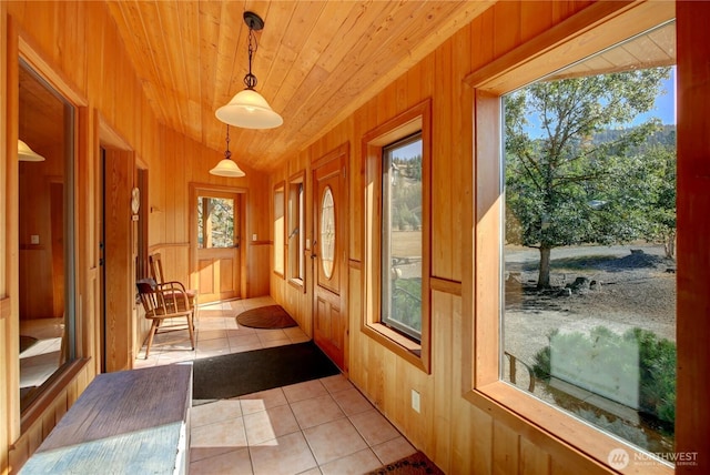 doorway featuring light tile patterned floors, wooden walls, and wood ceiling