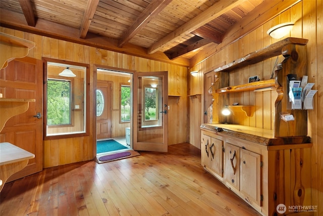 foyer entrance with light wood-type flooring, beam ceiling, wooden walls, and wood ceiling