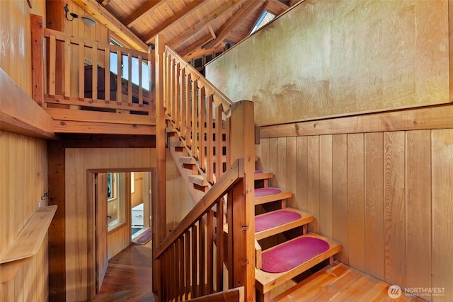 staircase featuring hardwood / wood-style floors, wooden ceiling, wooden walls, and lofted ceiling with beams