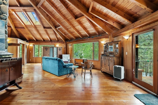 living area with lofted ceiling with skylight, wood walls, and light wood-type flooring