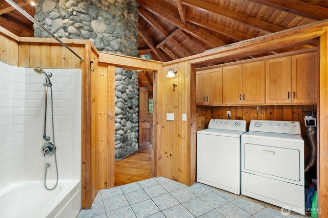 laundry area featuring wooden walls, light tile patterned floors, cabinet space, wood ceiling, and washer and clothes dryer