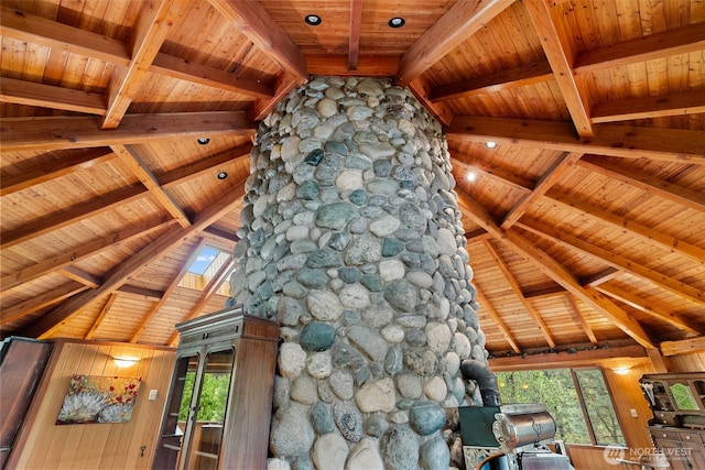 interior space featuring wooden ceiling, a skylight, a wood stove, and beam ceiling