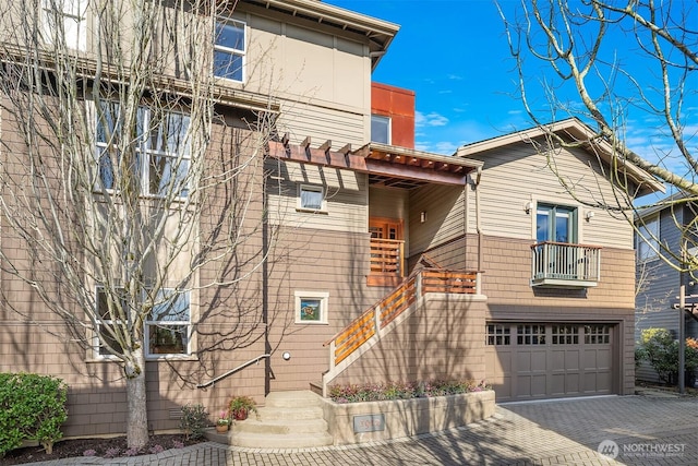 view of front of house featuring stairs, decorative driveway, a balcony, and an attached garage