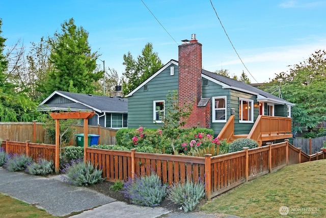 rear view of property featuring a lawn, a fenced front yard, and a chimney