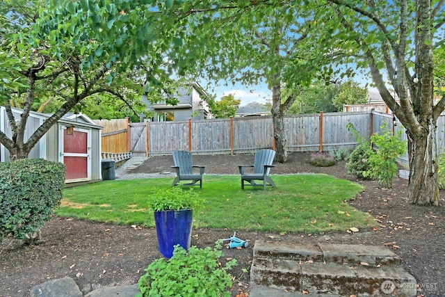 view of yard with an outbuilding, a fenced backyard, and a storage shed