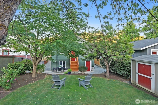 view of yard with an outbuilding, entry steps, a storage shed, and fence