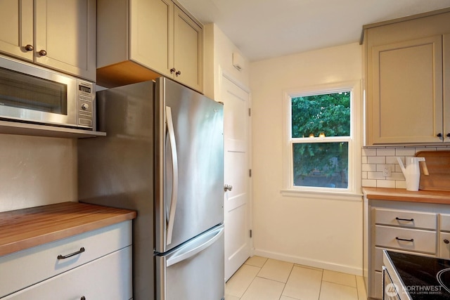 kitchen with light tile patterned floors, baseboards, tasteful backsplash, and stainless steel appliances