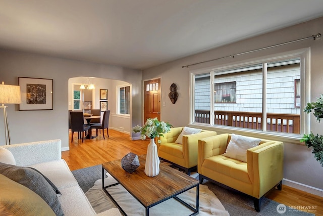 living room with wood finished floors, arched walkways, and baseboards