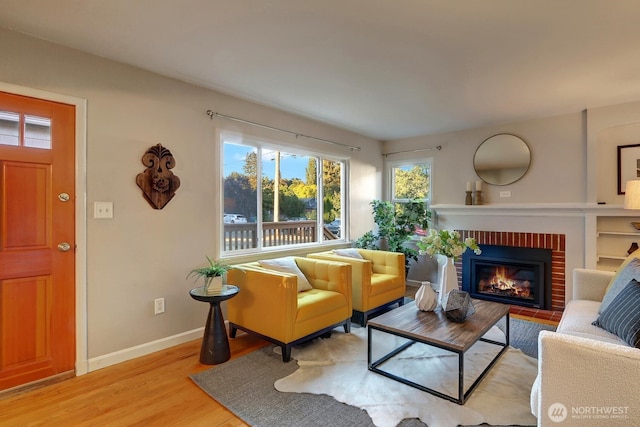 living room featuring light wood-style flooring, a fireplace, and baseboards