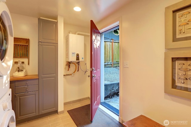 bathroom with recessed lighting, water heater, and stacked washing maching and dryer