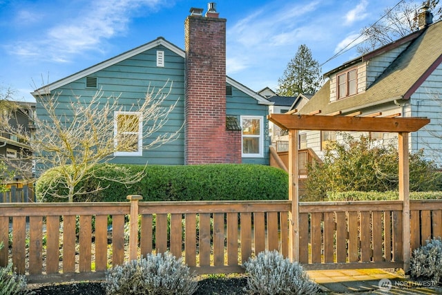 view of side of property with a chimney and fence