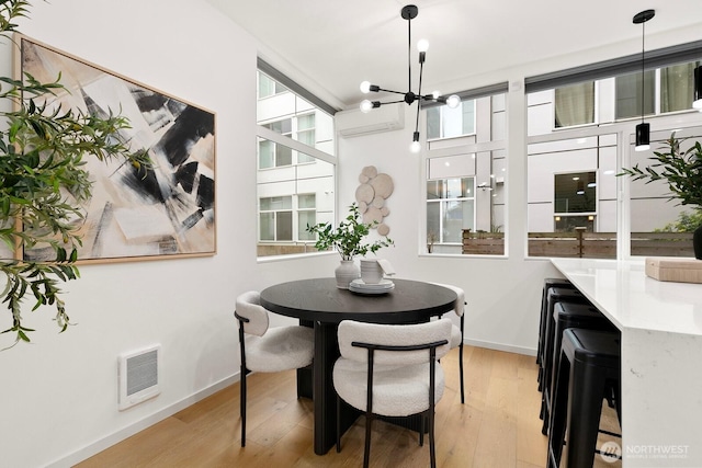 dining room with wood finished floors, visible vents, a wall mounted air conditioner, and a chandelier