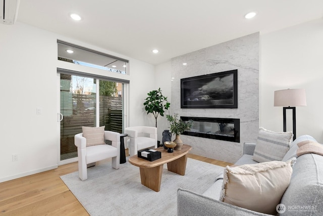 living room featuring recessed lighting, a fireplace, baseboards, and wood finished floors