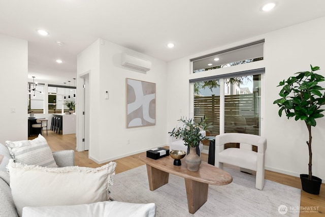 living area featuring recessed lighting, a wall mounted air conditioner, light wood-type flooring, and baseboards