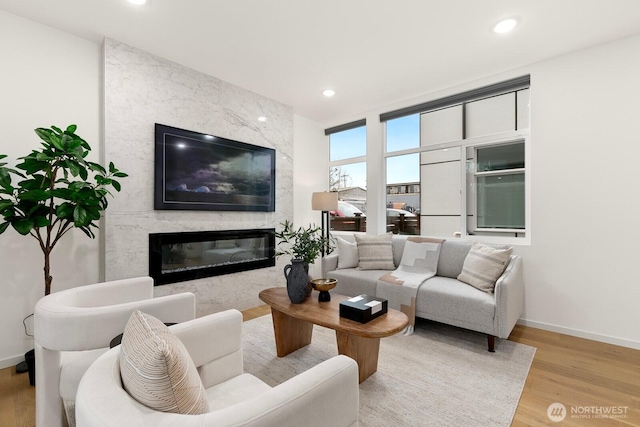 living room with recessed lighting, wood finished floors, baseboards, and a premium fireplace