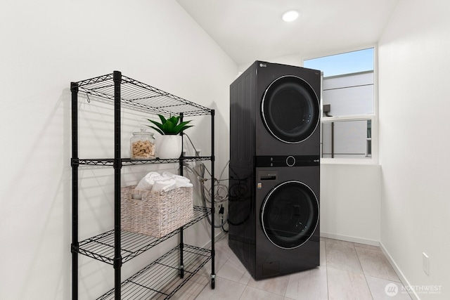 washroom with laundry area, baseboards, stacked washer and clothes dryer, and tile patterned floors