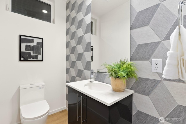 bathroom with toilet, vanity, baseboards, and wood finished floors