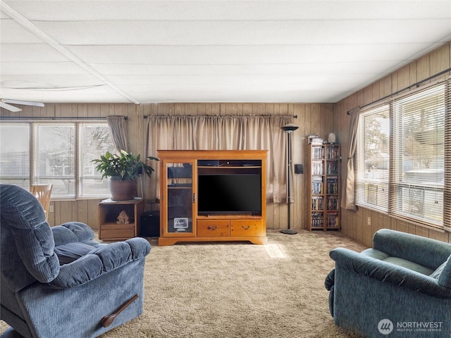 living room with a healthy amount of sunlight, wood walls, and carpet floors