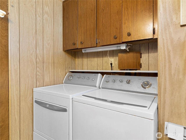 clothes washing area featuring washing machine and dryer and cabinet space