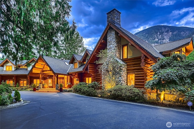 exterior space featuring a mountain view, a chimney, log exterior, and driveway