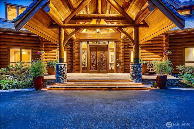 property entrance featuring log siding, french doors, and covered porch